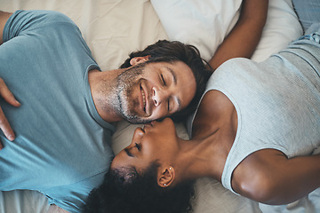 Image showing Interracial couple, kiss and relax on bed above for morning bonding, intimate relationship or love at home. Top view of woman kissing man while lying in bedroom for loving romance, care or affection