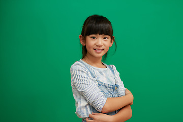 Image showing Happy, arms crossed and portrait of Asian girl in studio for smile, fashion and youth. Happiness, casual and cute with young child isolated on green background for mockup student and confidence