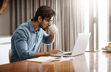 Image showing Man, remote work and drinking coffee at laptop in home at table for planning, research and online network. Focused male freelancer drink cup of tea while working on computer, internet and website