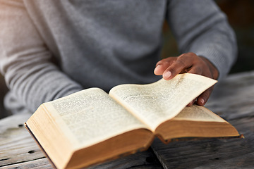 Image showing Hands, book and a man reading the bible at a table outdoor for faith or belief in god closeup. Religion, story and spiritual with a male christian sitting down to read for learning or worship
