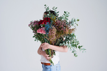 Image showing Nature, gift and woman with flowers, creative aesthetics and beauty against a grey background. Female person, model and girl with a floral present, bouquet and covering face with natural products