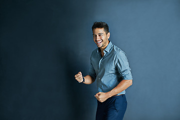 Image showing Celebration, fist pump and portrait of a businessman in a studio with achievement or winning. Happy, smile and professional male employee winner with success to celebrate isolated by blue background.