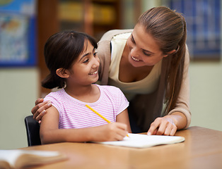 Image showing Study, education or learning with a student and teacher in a classroom together for writing or child development. School, scholarship and teaching with a woman educator helping a girl child in class