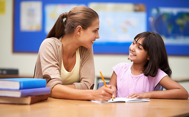 Image showing School, education or learning with a girl student and teacher in a classroom together for writing or child development. Study, scholarship and teaching with a woman educator helping a child in class