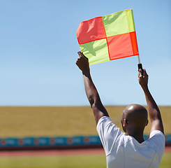 Image showing Flag, foul and man soccer referee in football match or game wave to stop play during sport training or workout. Hand, sports and person or assistant official raise or signal mistake in sky background