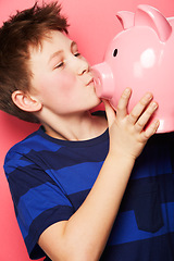 Image showing Happy boy, savings and kiss on piggy bank for investment, money or coins against a pink studio background. Little child or kid holding and kissing piggybank for financial freedom, cash or growth