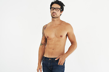 Image showing Portrait, shirtless and glasses with a sexy man model in studio on a white background for masculine desire. Body, tattoo and manly with a handsome young male nerd posing topless for rugged sensuality