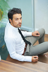 Image showing Portrait, serious and stairs with a business man in a modern office at work for progress. Confidence, professional or staircase with a handsome young male employee sitting on steps in his workplace