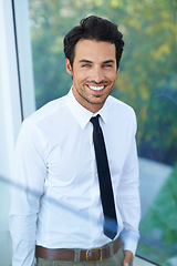 Image showing Portrait, corporate and smile with a business man in a modern office at work for success. Happy, glass window or career and a handsome young male employee standing in his workplace with ambition