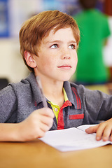 Image showing School, learning and kid writing in his book while listening to lesson in the classroom. Academic, knowledge and young boy child student doing an education activity, studying or homework by her desk.