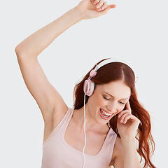 Image showing Young woman, headphones and dance in studio with music, streaming and happiness by wall background. Girl, student or isolated model with listening to audio app, sound and internet radio for dancing