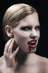 Image showing Portrait, blood and a female vampire in studio on a dark background for halloween or cosplay. Fantasy, horror or scary with an attractive young woman monster posing as an evil and feminine creature