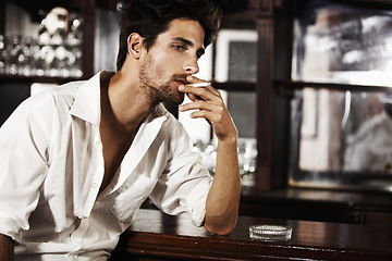 Image showing Handsome man, smoking and on bar counter or cigarette burning on hand and thinking about cancer. Sexy, male person face or with ash tray or customer relaxing with nicotine and smoke idea after work