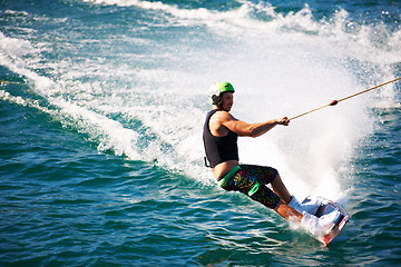 Image showing Summer, wakeboard and water sports with man in lake for action, challenge and travel vacation. Wave, adrenaline junkie and fitness with guy surfing in sea for health, adventure and speed