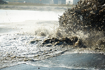 Image showing Pollution, sewer and waste in water to ocean from industrial for construction, pipeline and danger. Environment, texture and industry with wave from sewage on shoreline for stream, foam and mud