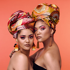 Image showing African fashion, makeup and portrait of women on orange background for cosmetics, beauty and accessory. Glamour, designer and face of female people in exotic jewelry, luxury style and scarf in studio