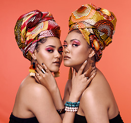 Image showing African fashion, cosmetics and portrait of women on orange background with accessory, makeup and beauty. Glamour, luxury and female people in exotic jewelry, traditional style and scarf in studio