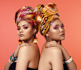 Image showing African fashion, cosmetics and portrait of women on orange background with accessory, makeup and beauty. Glamour, luxury and female people in exotic jewelry, traditional style and scarf in studio