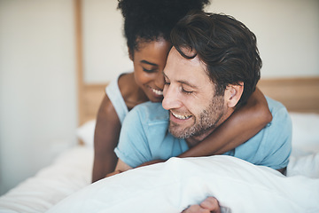 Image showing Happy couple, bed and smile in hug for morning, relax or bonding relationship at home. Interracial man and woman smiling and hugging in joyful happiness for relaxing weekend together in the bedroom