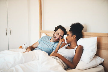 Image showing Interracial couple, laughing and relax on bed for morning bonding, funny relationship or joke at home. Happy woman and man with smile, laugh and lying in bedroom for fun talk or conversation indoors