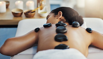 Image showing Woman, relax and rock massage at spa for skincare, beauty or body treatment on bed at resort. Calm female lying in relaxation with hot rocks or stone pile on back in therapy, zen or wellness at salon