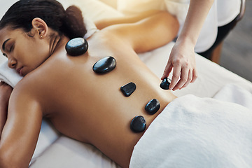 Image showing Woman, hands and stone massage at spa for skincare, beauty or body treatment on bed at resort. Calm female lying in relaxation with masseuse, hot rocks and back for therapy, zen or wellness at salon