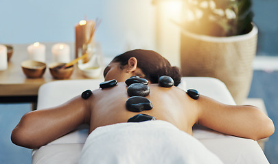 Image showing Woman, relax and rock in back massage at spa for skincare, beauty or body treatment on bed at resort. Calm female lying in relaxation with hot rocks or stone pile in therapy, zen or wellness at salon