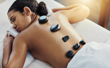 Image showing Woman, sleeping and stone massage at spa for skincare, beauty or body treatment on bed at resort. Calm female lying in relaxation with hot rocks on back for physical therapy, zen or wellness at salon