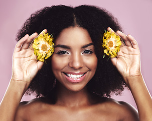 Image showing Happy woman, hair and daisy flowers in studio, pink background and floral aesthetic of natural beauty. Portrait, face and african model with yellow plants, afro and smile for vegan cosmetic skincare