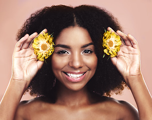 Image showing Portrait of happy woman, hair care and beauty with yellow flowers on studio background. African model, natural skincare and daisy plants in afro for sustainable cosmetics, floral aesthetic and smile