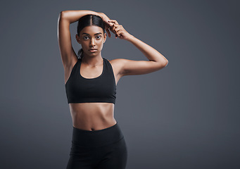 Image showing Portrait, space and stretching with an athlete woman in studio on a gray background for fitness or health. Exercise, workout or warm up and an attractive young female model training with mockup