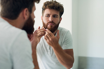 Image showing Face, beauty and beard with a man in the bathroom of his home in the morning for fresh hygiene. Mirror, reflection and care with a handsome young male person checking his skin for facial treatment