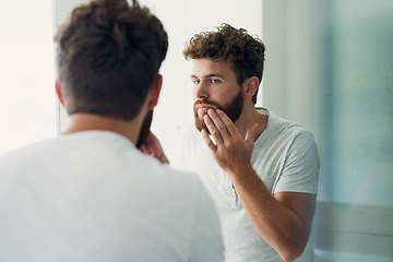 Image showing Skincare, beauty and beard with a man in the bathroom of his home in the morning for fresh hygiene. Mirror, reflection and self care with a handsome young male person checking his face or skin