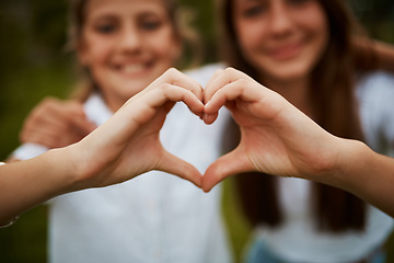 Image showing Love hand sign, happy sisters in garden with fun relationship, bonding and care with siblings. Heart hands, girls and nature, kindness and friendship for teenagers in park for quality time together.