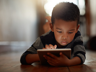 Image showing Learning, little boy and on digital tablet or playing games or streaming video on the internet and lying on the floor at home on bokeh. Technology, device and male child downloading app or reading