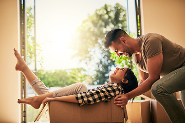 Image showing New home, funny and couple pushing box, having fun and bonding in apartment. Real estate, laughing and man and woman in cardboard, play and enjoying quality time together while moving into property.