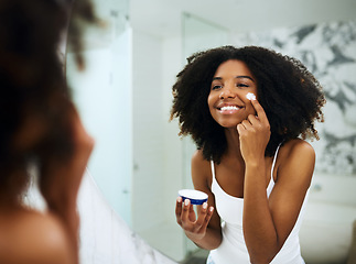 Image showing Skincare, bathroom mirror and black woman with cream, smile and morning dermatology routine. Health, wellness and luxury skin care at home, girl in reflection with lotion on face for facial treatment