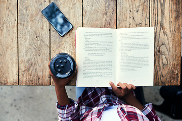 Image showing Woman, hands and book of student reading with coffee for literature on wooden table above at cafe. Top view of female person hand and story novel for knowledge, language or information at coffee shop