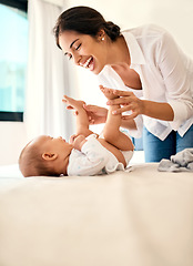 Image showing Happy, love and a mother with her baby on the bed in their home together for playful bonding. Family, children and a young mama spending time with her newborn infant in the bedroom for fun or joy