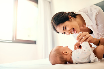 Image showing Happy, love and a mother with her baby in the bedroom of their home together for playful bonding. Family, children and a young mama spending time with her newborn infant on the bed for fun or joy