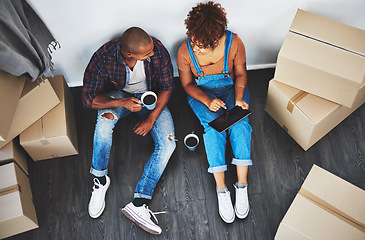 Image showing Boxes, new home and couple with a tablet planning on their living room floor together with coffee. Technology, real estate and top view of young people doing online property research in a house