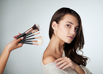 Image showing Makeup, face brush and beauty of a woman in studio with natural glow on skin. Portrait of female person on a grey background with a hand for cosmetology tools, powder cosmetics and facial dermatology