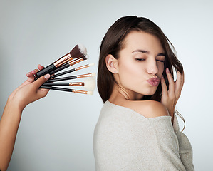 Image showing Face, makeup brush and beauty of a woman in studio with a natural glow and shine. Headshot of a female person on a grey background with a hand and lips for cosmetology, facial cosmetics and skin care