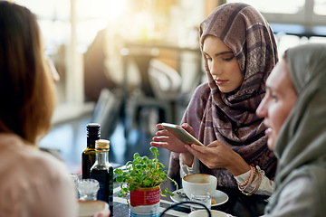 Image showing Friends, phone and Muslim women in cafe, bonding and talking together. Coffee shop, cellphone and Islamic girls, group or people relax, conversation and discussion for social meeting in restaurant.