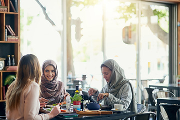 Image showing Friends, happy and Muslim women in restaurant, eating and talking together. Lunch, smile and Islamic girls, group or people chatting, conversation and discussion for social meeting, bonding and food.