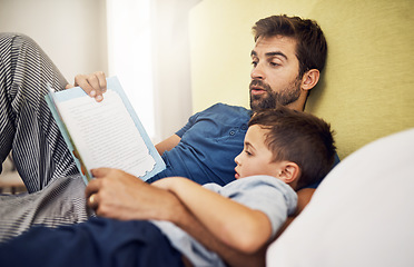 Image showing Family, father and son with a book, home or reading with bonding, development and relax in a bedroom. Happy parent, male child or kid with dad, literature and learning on a bed, love and storytelling