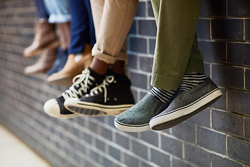 Image showing Brick wall, students feet and friends outdoor on university campus together with sneakers. Relax, youth and foot at college with people legs ready for education, study and urban shoes while sitting