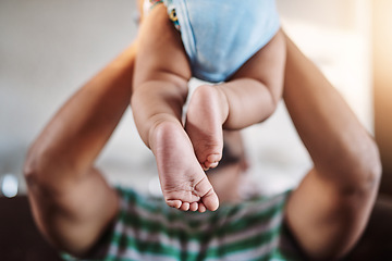 Image showing Closeup, legs and baby with father, love and playing with joy, happiness and bonding in the lounge. Zoom, dad and infant in the air, home and games with child development, fun and family on a couch