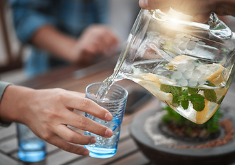 Image showing Hands, closeup and water into a glass, outdoor and social gathering with friends, drink and cool down. Zoom, people and friends with clear liquid, ice and lunch with fresh mint, lemon and natural