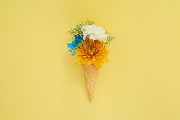 Image showing Floral ice cream in a cone in a studio for art, creativity or decoration with fresh and colorful bouquet. Creative, still life and blossom flowers or plants in a dessert isolated by yellow background